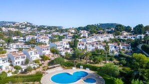 A residential area with a large circular swimming pool surrounded by greenery and white houses with red-tiled roofs. - Casita Blanca by Interhome (Moraira)