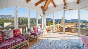 A spacious balcony with a view of the surrounding landscape, furnished with a sofa, chairs, and a table.