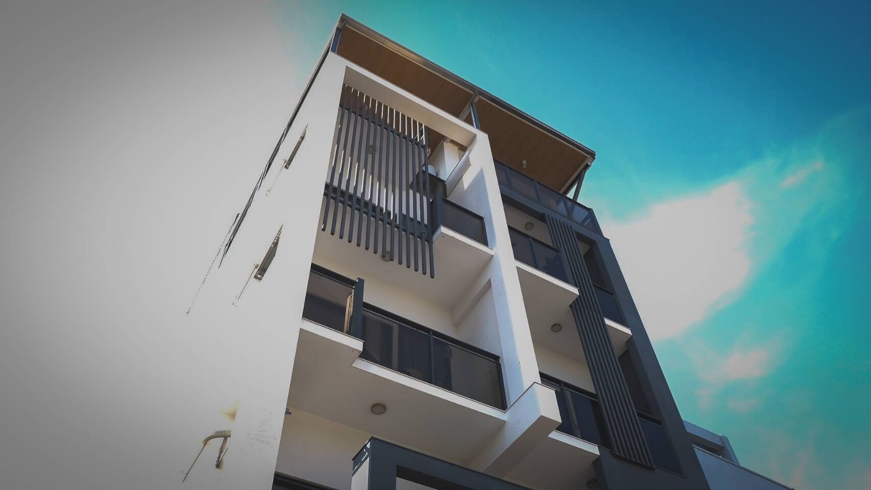 Un edificio de varios pisos con balcones y grandes ventanales.
