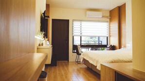 A compact hotel room with a bed, a desk, a chair, and a window with blinds. - Moker House  (Jincheng)