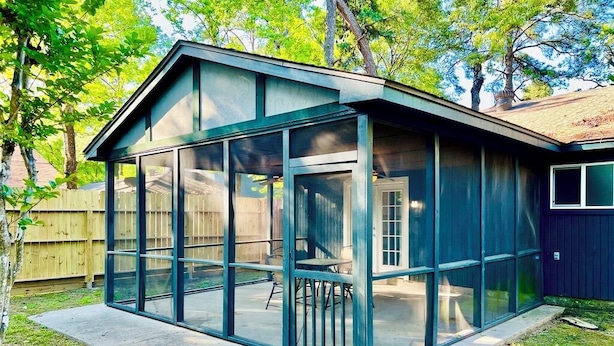 A modern house with a large glass enclosure, a patio, and a wooden fence in the background. - House 3-Bedroom 2-Full Baths FREE Garage Parking, Washer, Dryer in The Woodlands (Spring)