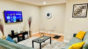 A living room with a flat-screen TV, a clock, and a framed artwork on the wall. - House 3-Bedroom 2-Full Baths FREE Garage Parking, Washer, Dryer in The Woodlands (Spring)