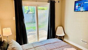 A bedroom with a bed, a TV mounted on the wall, and a sliding glass door leading to a backyard. - House 3-Bedroom 2-Full Baths FREE Garage Parking, Washer, Dryer in The Woodlands (Spring)