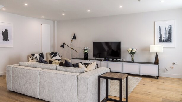 Een moderne woonkamer met een bank, een televisie en decoratieve objecten.