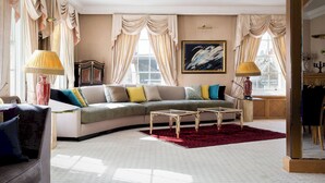 Ein Wohnzimmer mit einer Couch, zwei Beistelltischen, einem roten Teppich und einem Gemälde an der Wand.