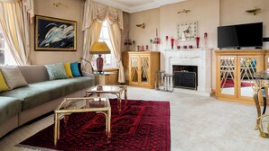 Ein Wohnzimmer mit einer Couch, einem Couchtisch, einem Kamin und einem Fernseher.