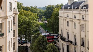 Blick auf eine Stadtstraße mit Gebäuden, Bäumen und einem Doppeldeckerbus.