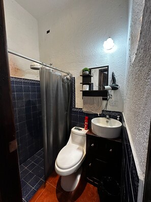 Een badkamer met toilet, wastafel en douchegordijn.