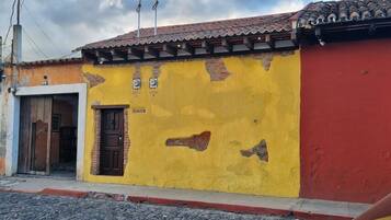 Un edificio con una pared amarilla y una sección roja, que presenta una puerta y una ventana.