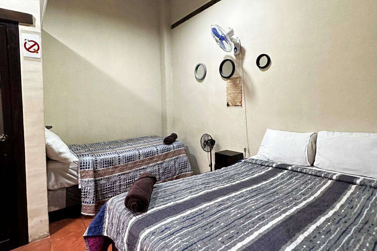 Una habitación con dos camas, un ventilador de techo y una lámpara.