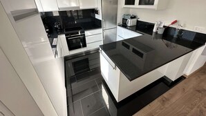 A modern kitchen with white cabinetry, black countertops, and stainless steel appliances.