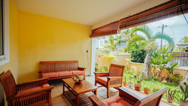 A patio with wooden furniture, including a sofa and chairs, and a table with fruit.