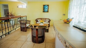 A dining area with a wooden table and chairs, a sofa, and a decorative wall piece.