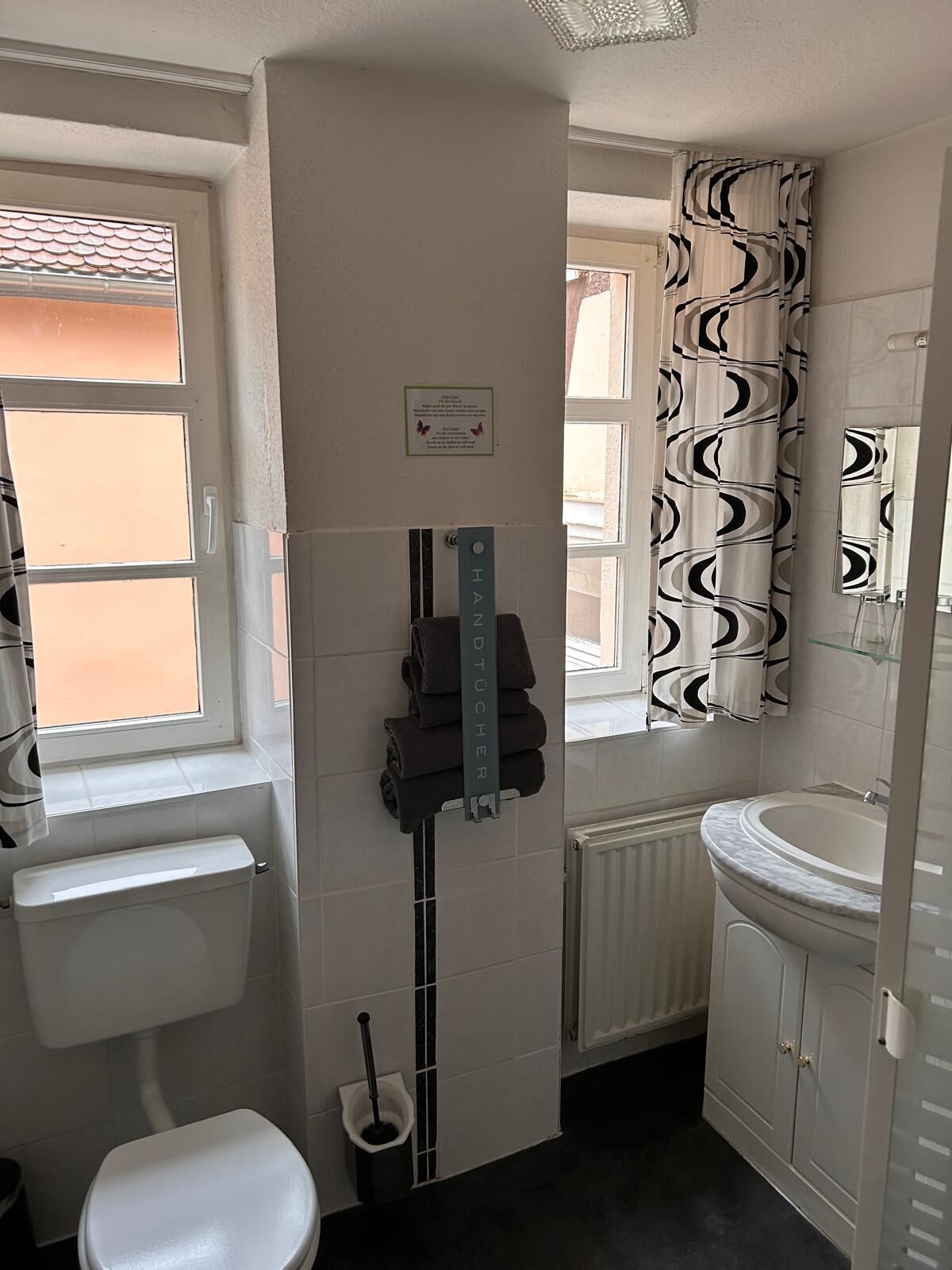 Ein Badezimmer mit Toilette, Waschbecken und Fenster.