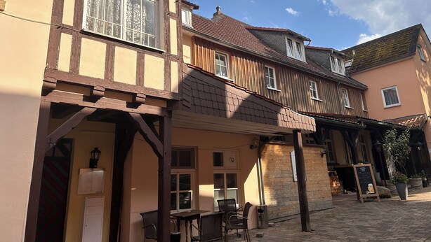 A traditional half-timbered building with a covered outdoor seating area and a visible signboard.
