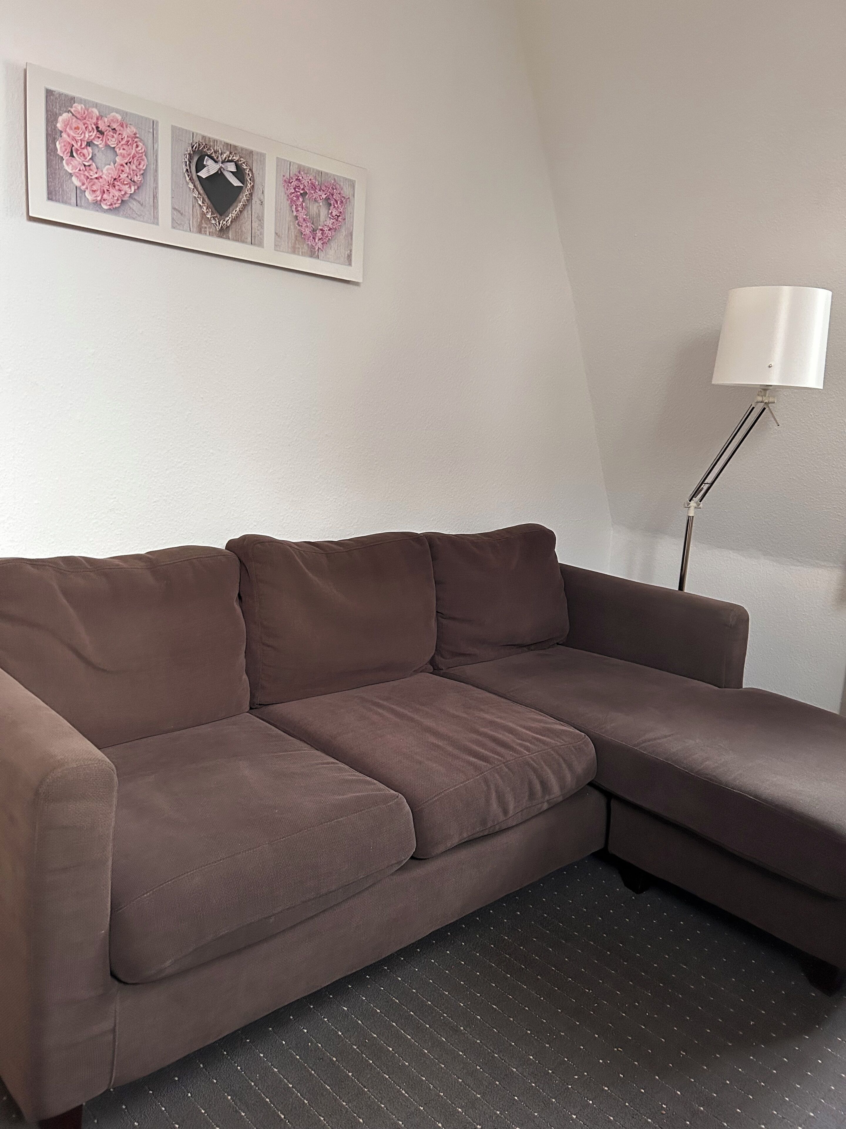 Een bruine modulaire bank in een kamer met een witte muur en een vloerlamp.