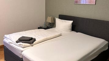 Ein ordentlich bezogenes Bett mit weißer Bettwäsche, einem dunklen Kopfteil und einem Gemälde an der Wand.