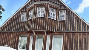 A building with a wooden exterior and multiple windows. There is a patio area with outdoor seating and a table.