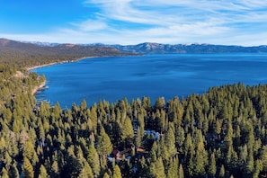 A coastal landscape with dense forest, a clear blue lake, and distant mountains. - Lundy Bearden Serene Tahoe Retreat With Deck, Fireplace, and Forest Views (Carnelian Bay)