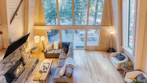 Una sala de estar acogedora con chimenea, sofás y vistas a una terraza y árboles.