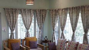 A cozy living room with a sofa, armchairs, a coffee table, and a ceiling fan. - DeerWood Cottages (Tehri)