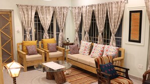 A cozy living room with a sofa, two armchairs, a coffee table, and a patterned rug. - DeerWood Cottages (Tehri)