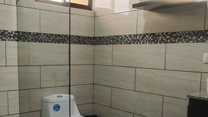 Ein Badezimmer mit Toilette, Dusche und einer kleinen Ablage für Kosmetikartikel.
