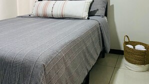 Ein Schlafzimmer mit Bett, einer Kopfteil, einer Wandklimaanlage und einem Korbwesen auf dem Boden.