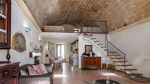 A spacious living area with a high ceiling, a staircase, and a dining area. - GuestHost - Domus Tua (Matera)