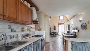 A kitchen with wooden cabinets, a tiled backsplash, and a view into a dining area. - GuestHost - Domus Tua (Matera)