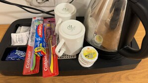 Ett bricka med en vattenkokare, två vita muggar och flera förpackningar tandkräm från Colgate.