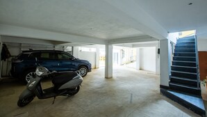 Un parking où se trouvent un SUV bleu et un scooter.
