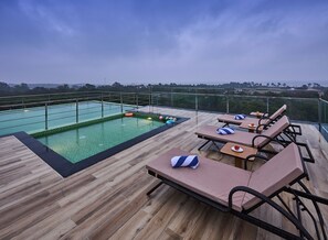 Un área de piscina en la azotea con sillones de descanso y una piscina.