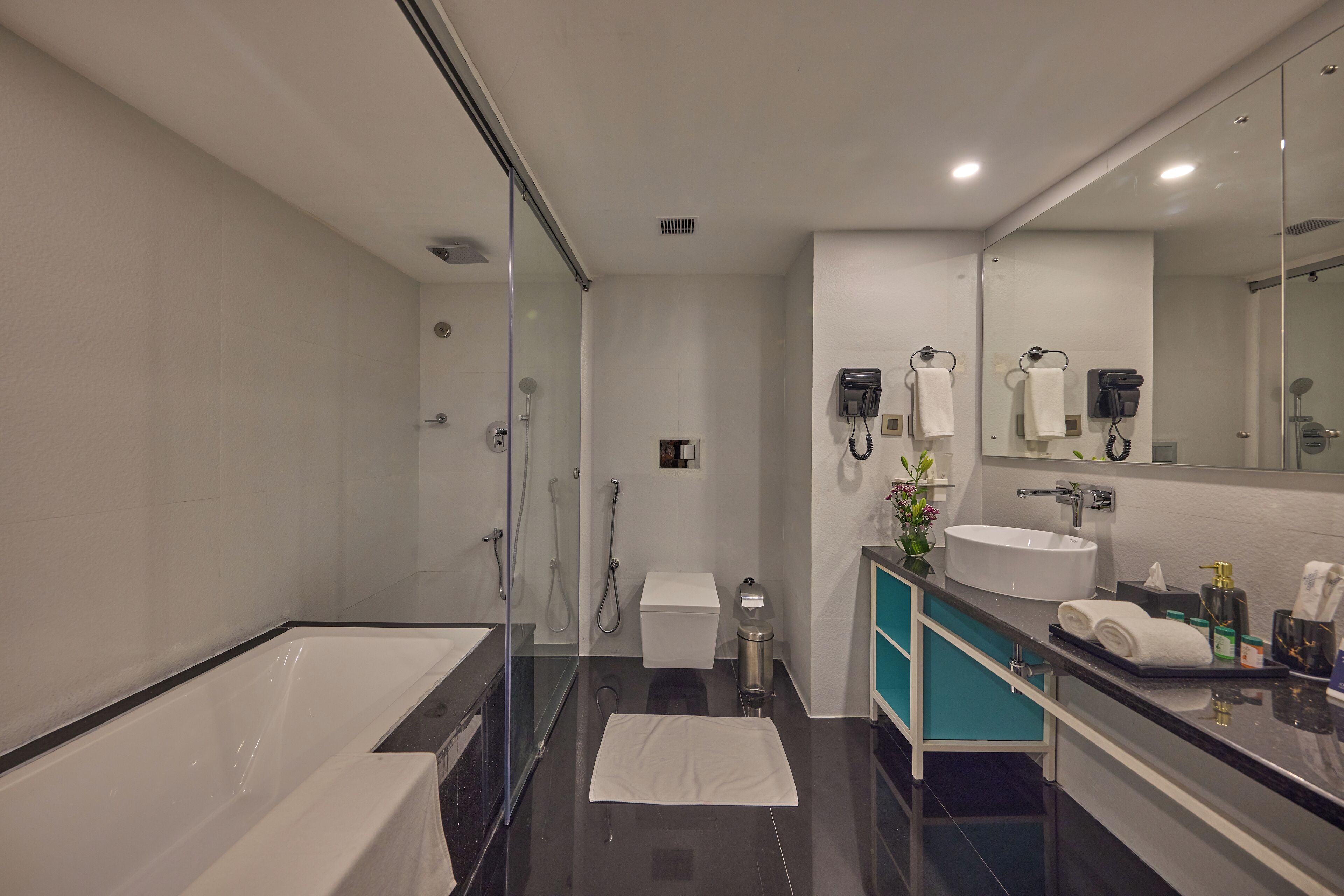 A modern bathroom with a bathtub, a sink, a toilet, and a shower area.