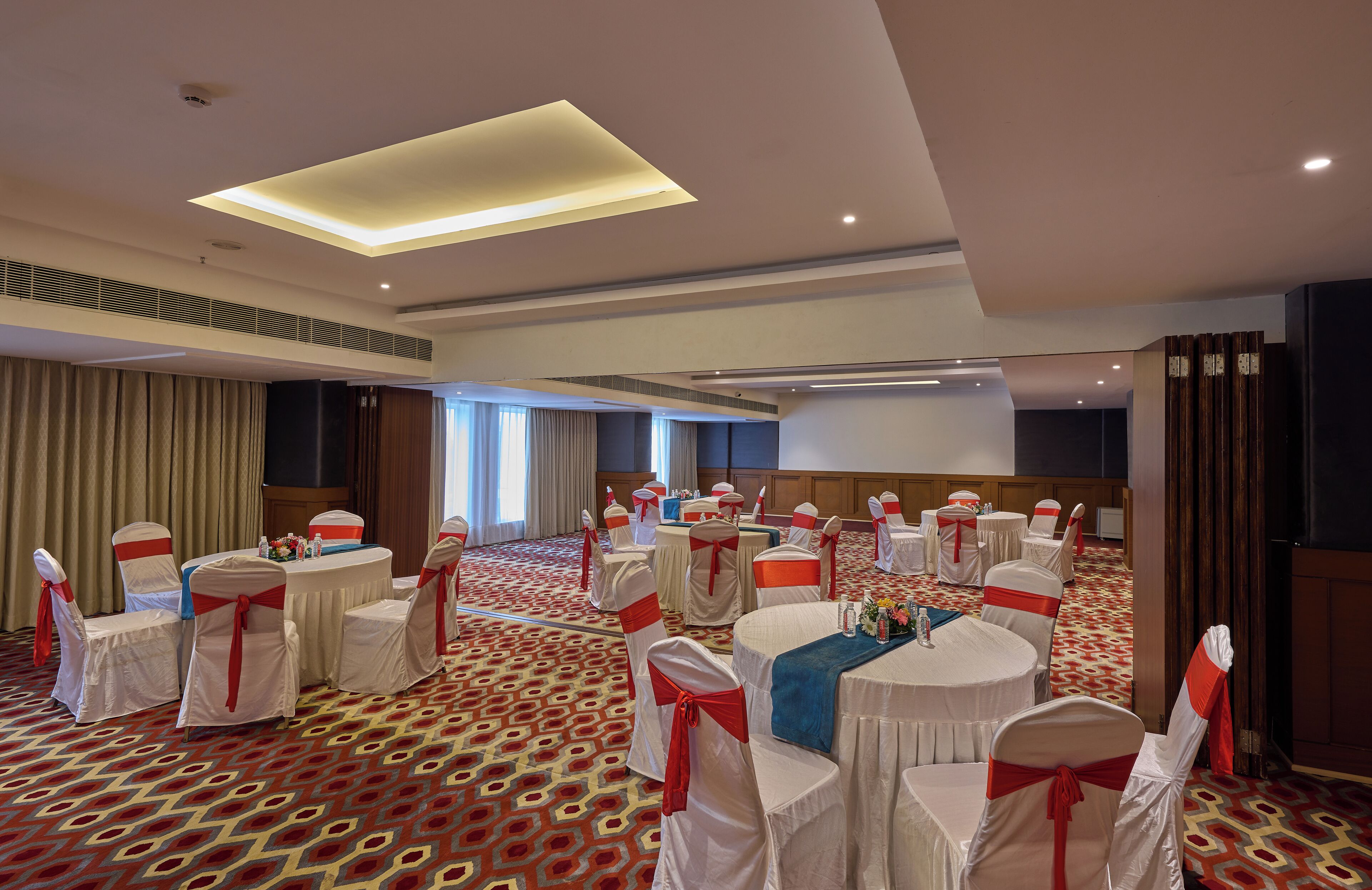 A conference room with round tables and chairs, a patterned carpet, and a modern ceiling design.