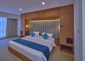 Una habitación de hotel con una cama grande, cabecera de madera y estante empotrado.
