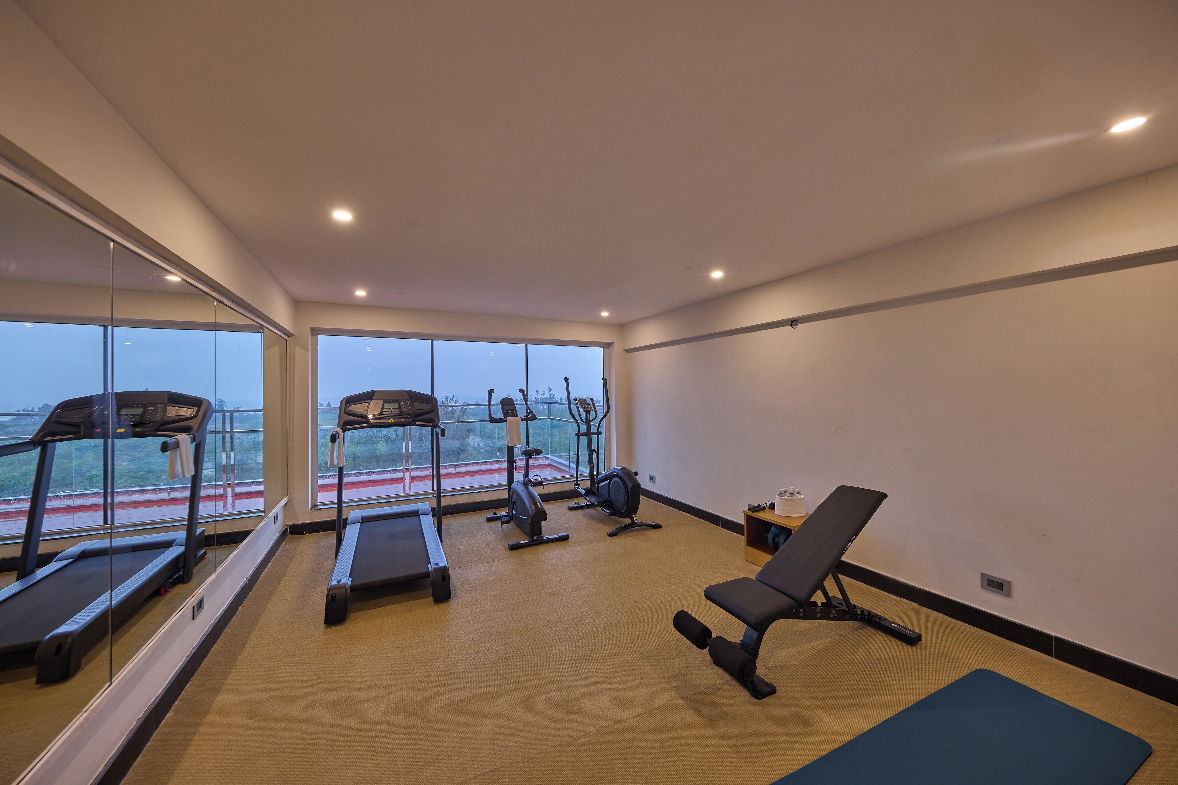 Un gimnasio con cintas de correr, elípticas y una banca.