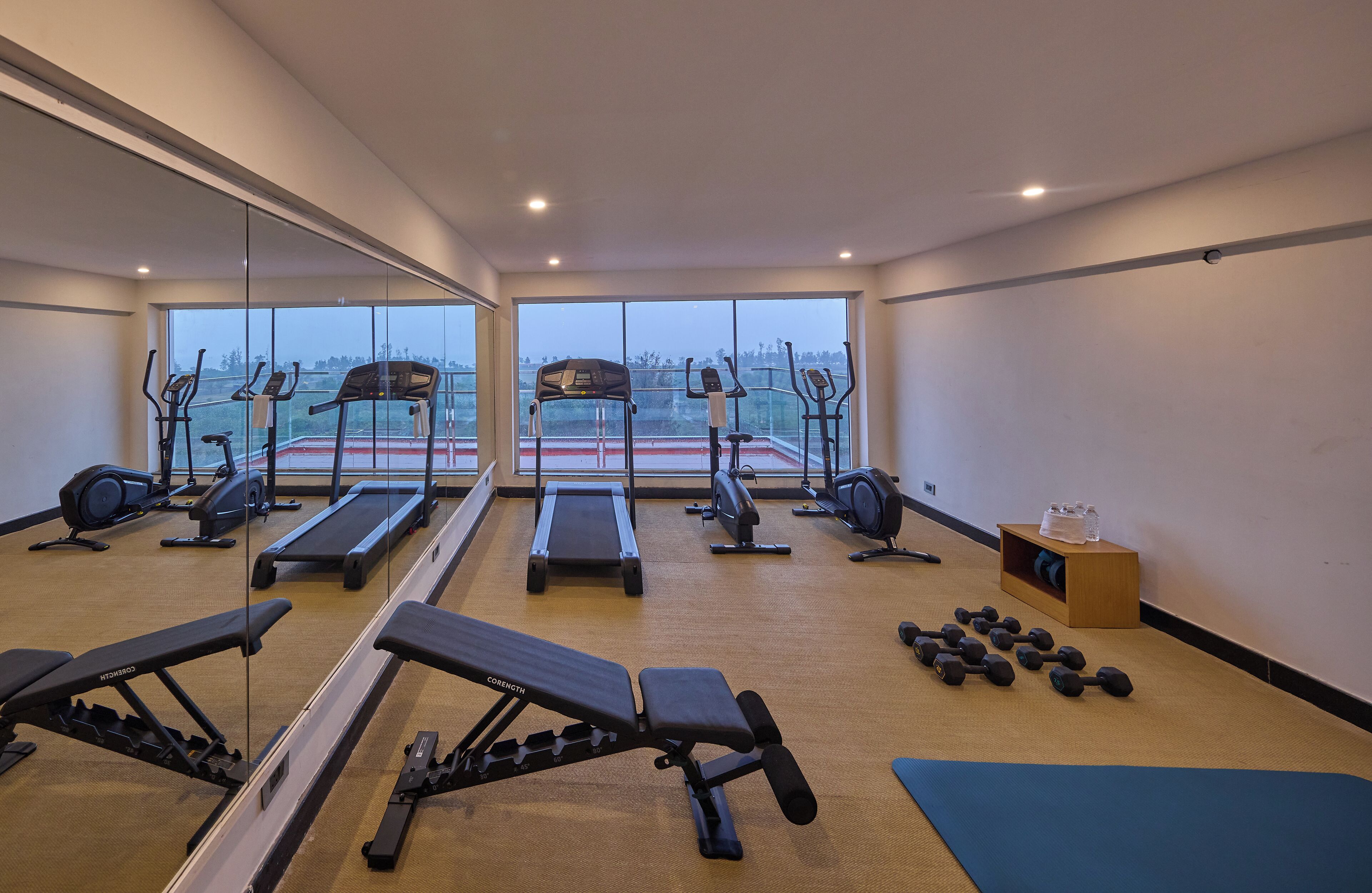 A gym with cardio equipment, weight benches, and dumbbells.
