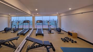 A gym with cardio equipment, weight benches, and dumbbells.