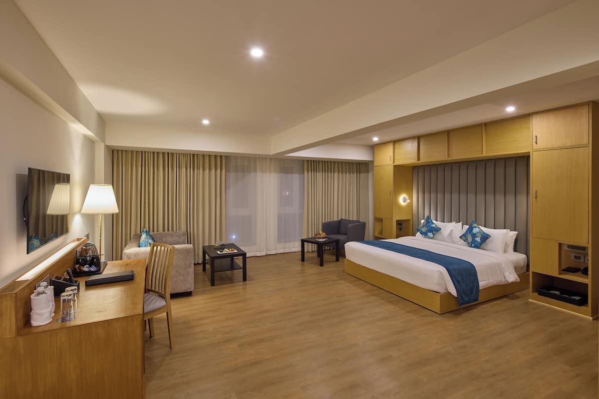 Une chambre d’hôtel avec un grand lit, un bureau, une chaise, une télévision et une armoire.