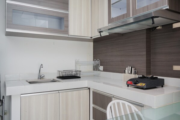 Una cocina moderna con encimera blanca, pileta de acero inoxidable y armarios de madera.
