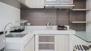 Eine moderne Küche mit Spüle aus Edelstahl, Holzschränken und einem Esstisch aus Glas.