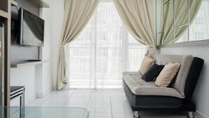 Ein modernes Wohnzimmer mit einer Couch, einem Flachbildfernseher und einem großen Fenster mit Vorhängen.