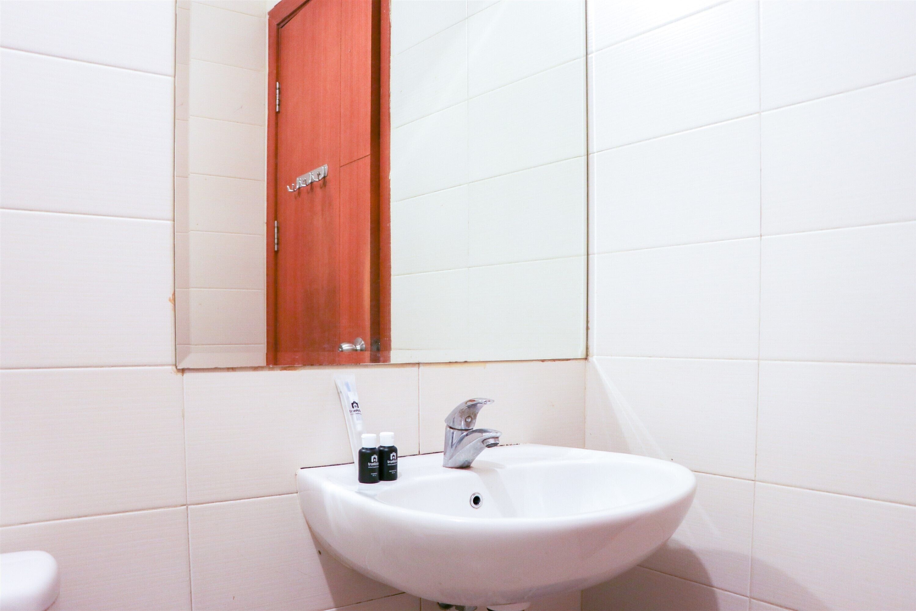 A bathroom with a white sink, a mirror, and a wooden cabinet.