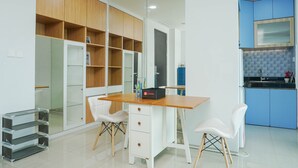 A modern kitchen with blue cabinets, a wooden countertop, and a white dining area with two chairs. - Elegant And Spacious 1Br At Citralake Suites Apartment (Jakarta)