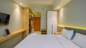 Une chambre d’hôtel équipée d’un lit, d’une télévision, d’un bureau et d’une armoire.