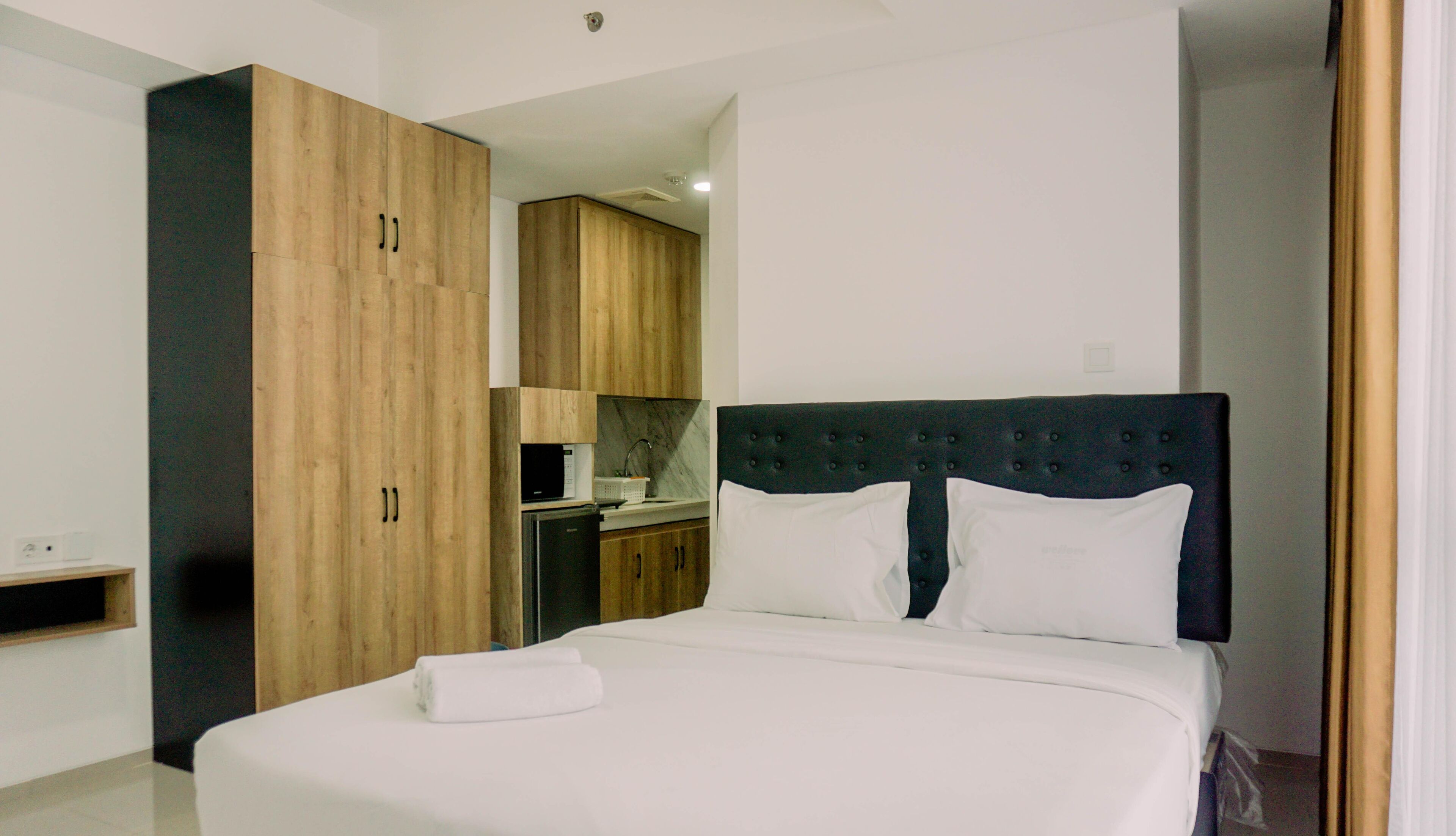 A hotel room with a bed, a wardrobe, and a kitchenette.