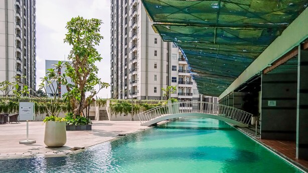 A rooftop pool with a bridge, surrounded by high-rise buildings and potted plants. - Best Deal Studio Pacific Garden Apartment Alam Sutera (Tangerang)
