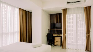 A hotel room with a bed, a desk with a chair, a television, and curtains. - Best Deal Studio Pacific Garden Apartment Alam Sutera (Tangerang)