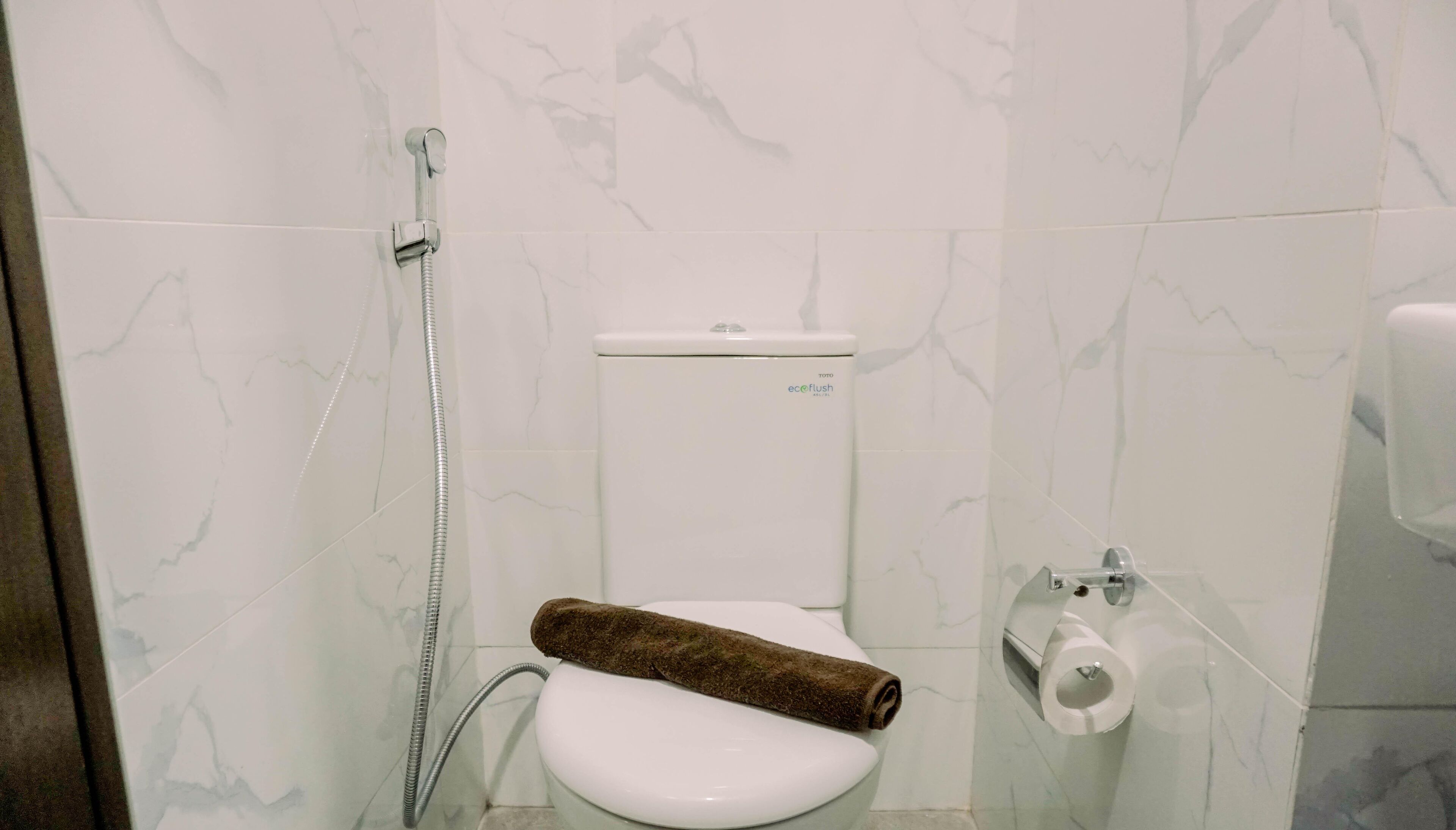 A bathroom with a toilet, a shower, and a toilet paper holder.